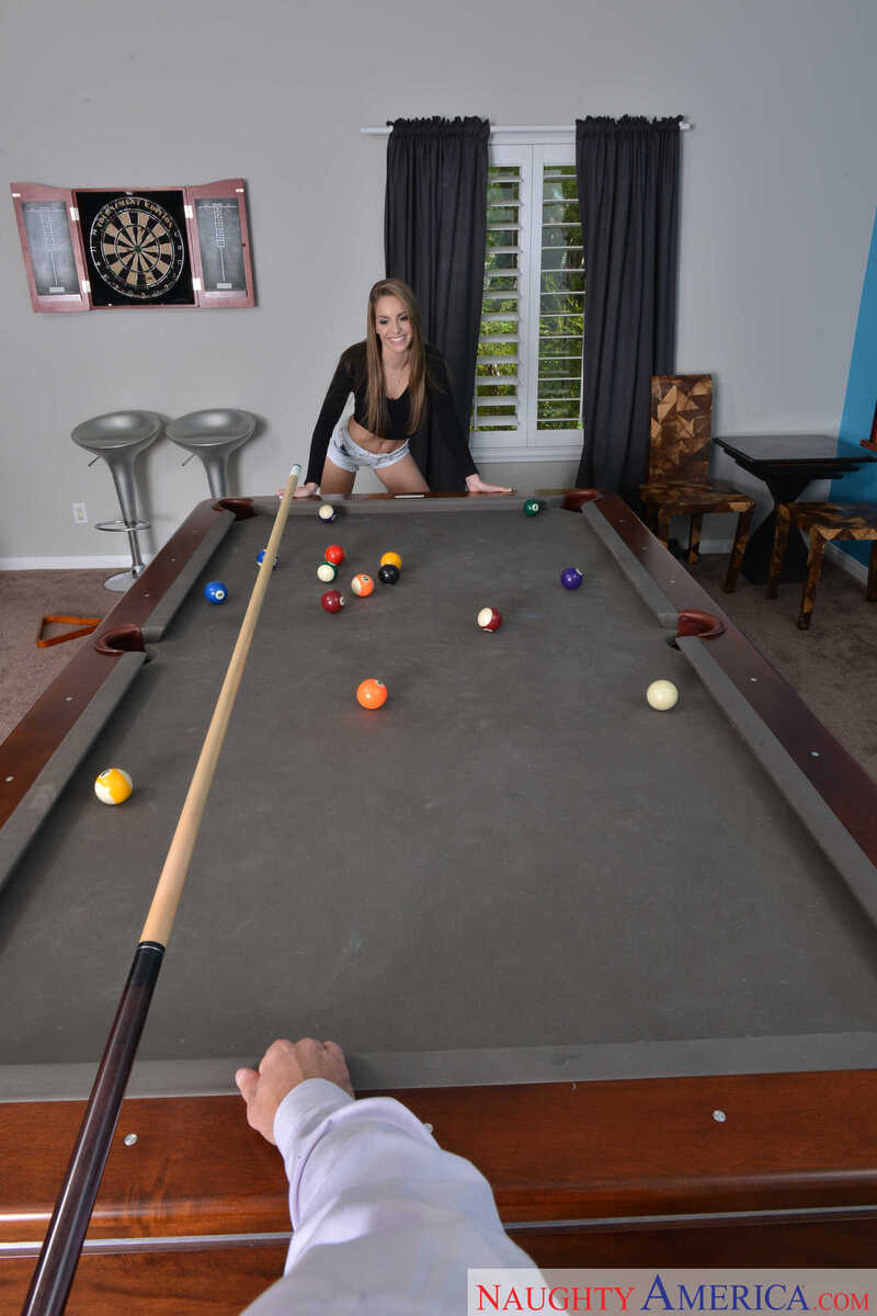 In the Kimmy Granger Naughty America porn scene 'Natural cutie Kimmy Granger plays strip pool with client before taking his balls on the table ' from American Daydreams, Kimmy Granger is playing pool with a cue stick.