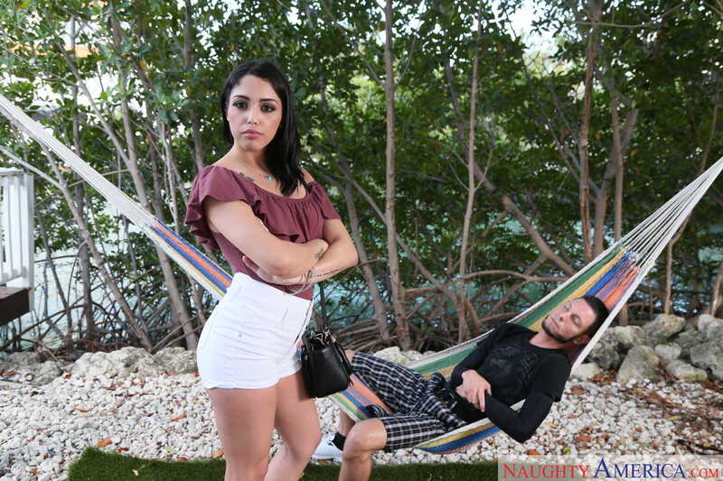 In the Vanessa Sky Naughty America porn scene 'Vanessa Sky fucking in the couch with her bubble butt' from Latin Adultery, Vanessa Sky is standing next to a hammock with a man in it.