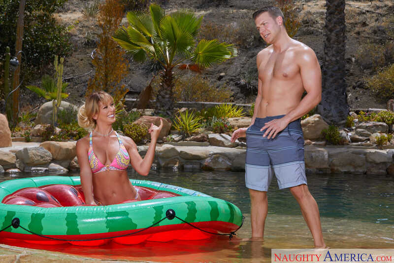 Naughty America Cherie DeVille porn: Cherie DeVille is in a bikini in a raft in a pool.