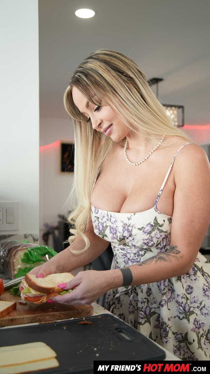 In the Katalina Kyle My Friend's Hot Mom porn scene 'Sexy Milf Katalina Kyle gets a cock meat sandwich from her son's friend', Katalina Kyle is making a sandwich in a white dress.