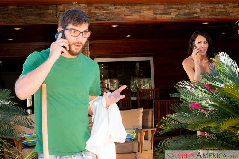 In the Reagan Foxx Naughty America porn scene 'Curvy MILF Reagan Foxx fucking in the bedroom with her tits' from My Friend's Hot Mom, Reagan Foxx is on the phone with a man in a green shirt.