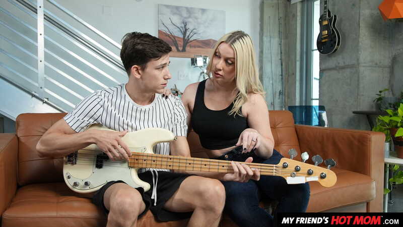 Scene from Naughty America Sydney Paige porn video 'Blonde MILF Sydney Paige teaches son's friend how to finger his bass guitar... and her pussy' where Sydney Paige and her friend are playing guitar together.