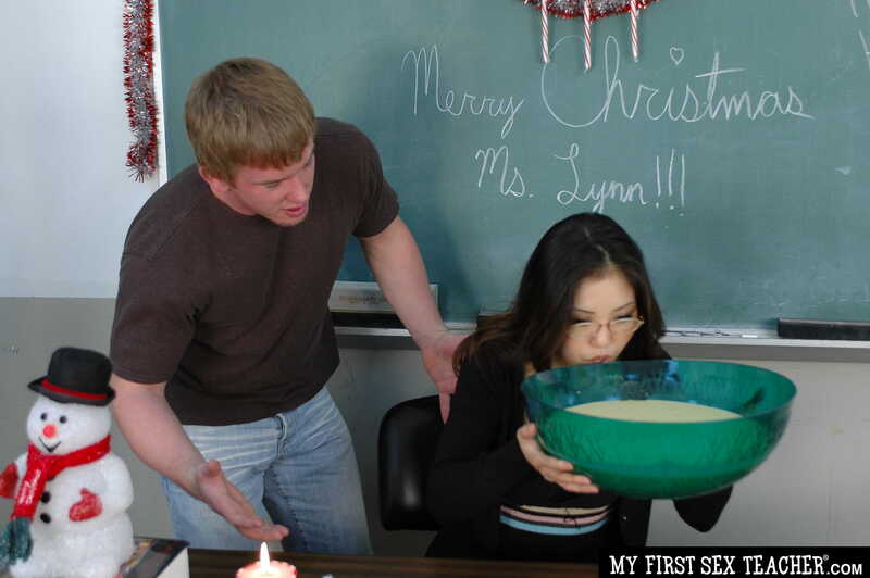 In the Kaiya Lynn My First Sex Teacher porn scene 'Beautiful Petite Asian Kaiya Lynn Gets Her Xmas Bonus In Her Wet Pussy', Kaiya Lynn is drinking from a bowl in front of a chalkboard.