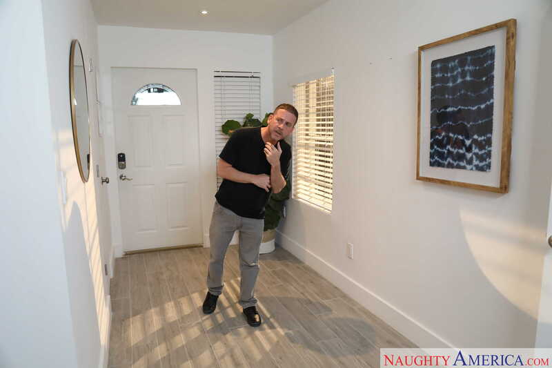 Naughty America Blaten Lee porn: Blaten Lee is standing in a hallway with a Naughty America.com watermark.