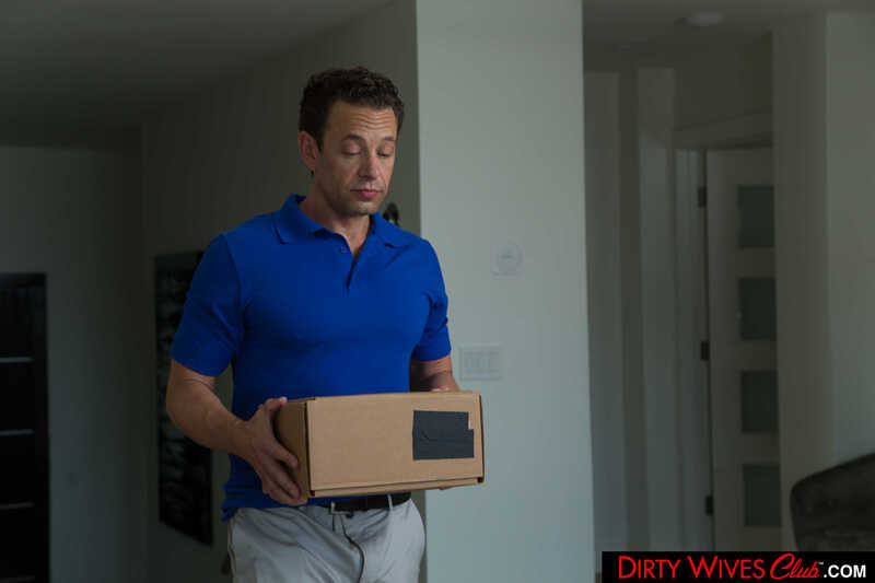 In the Kayley Gunner Naughty America porn scene 'Sexy blonde bombshell Kayley Gunner fucks delivery man with husband's permission' from Dirty Wives Club, Kayley Gunner is holding a box in her hands.