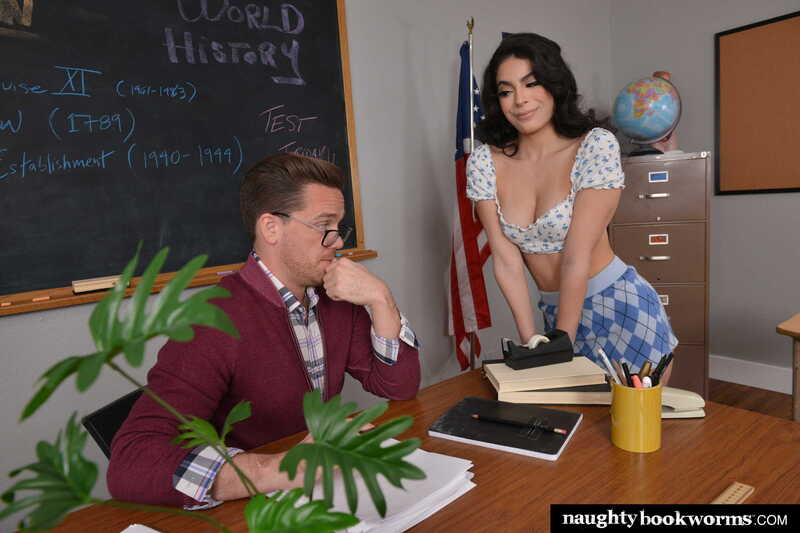 Scene from Naughty America Angel Gostosa porn video 'Brazilian school girl Angel Gostosa takes a ride on her professor's big cock' where Angel Gostosa is leaning over a man's desk in a World History classroom.