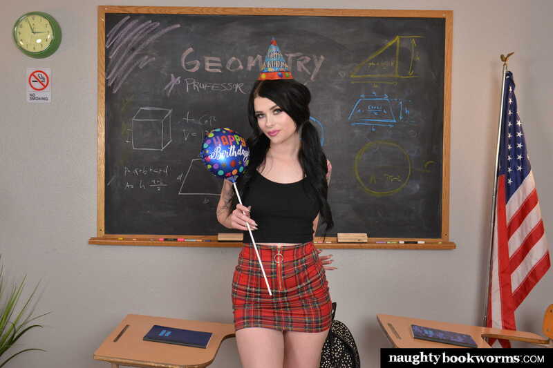 In the Kitty Lynn Naughty America porn scene 'Sexy school girl Kitty Lynn surprises professor with a birthday fuck' from Naughty Bookworms, Kitty Lynn is standing in front of a chalkboard wearing a short skirt.